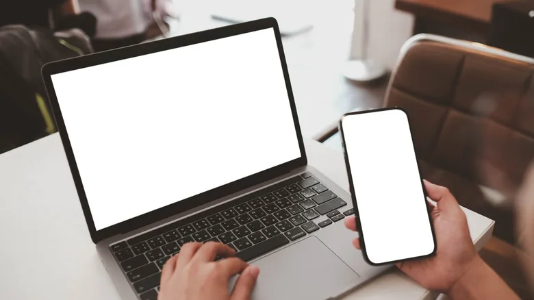 Person using a phone and laptop simultaneously