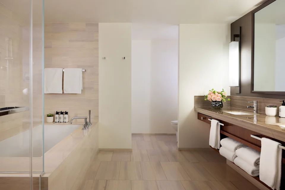 Junior Suite bathroom at The Langham, New York, featuring marble finishes, soaking tub and modern lighting.