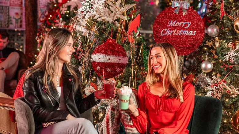 Two women toasting the holidays in a decorated bar.