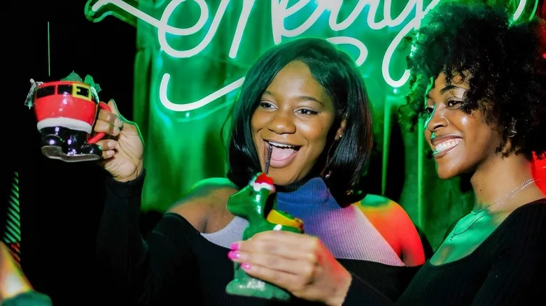 Two women toasting with Christmas drinks at the Miracle pop-up bar.