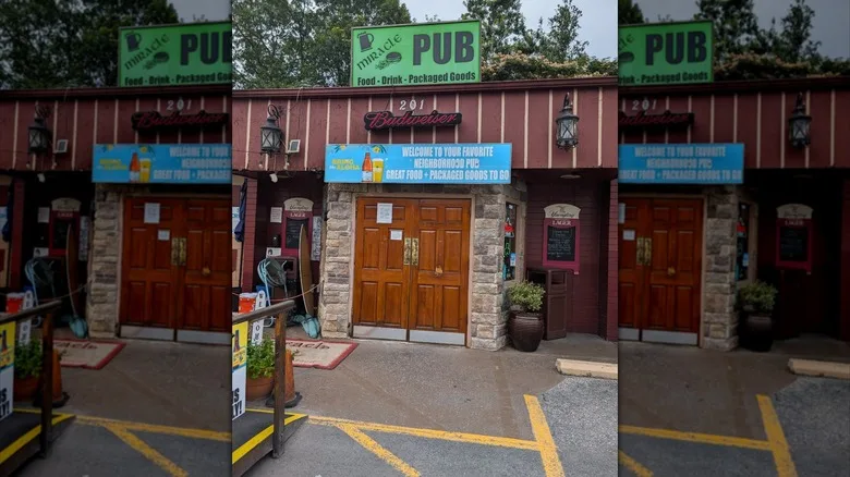 Exterior of Miracle Pub from parking lot with sign above wooden doorway
