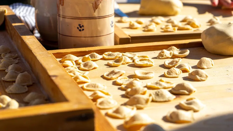 Ostuni, Puglia, Italy - 05 20 2022: Preparation of typical handmade pasta called "Orecchiette" in an outdoor space during the sunset light