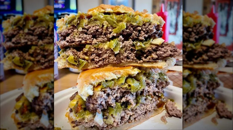 A close-up of two halves of a double burger with green chile stacked