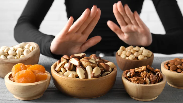 Hands making a gesture to refuse bowls of nuts