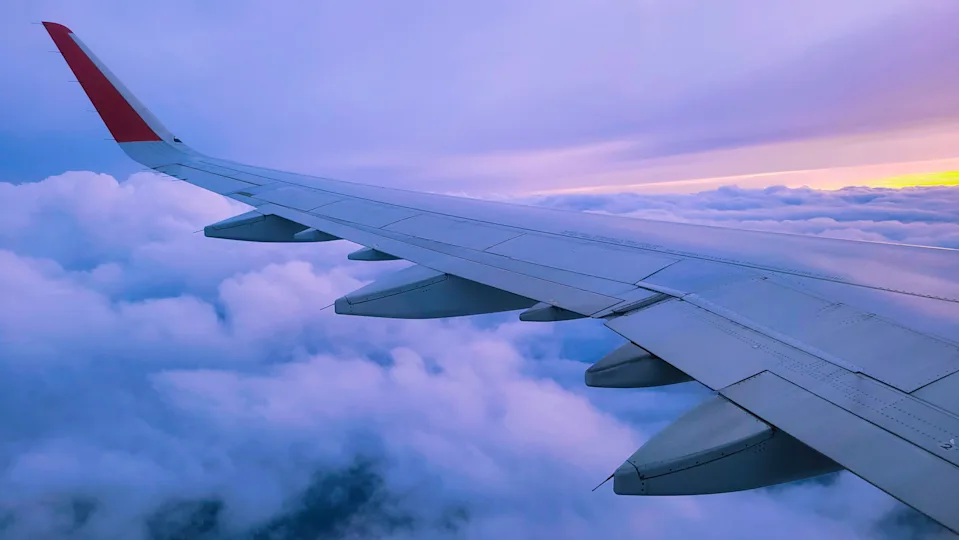 A plane wing flies over the clouds 