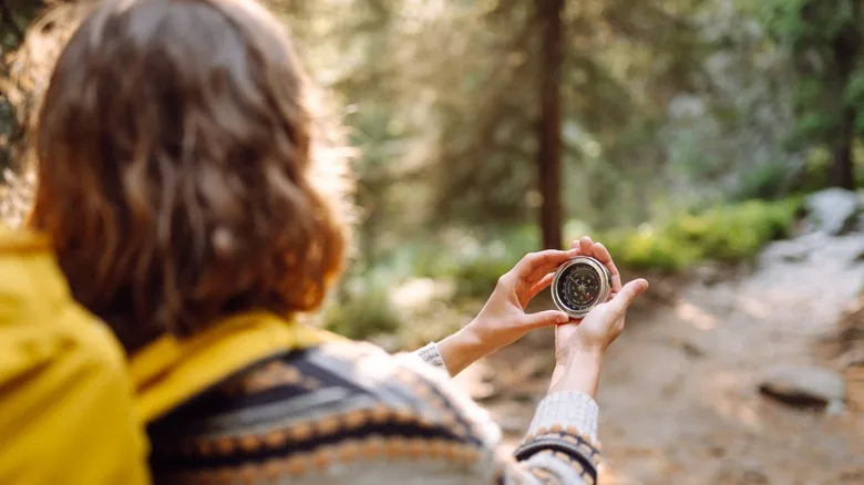 Woman hiker looking at a compass in the forest