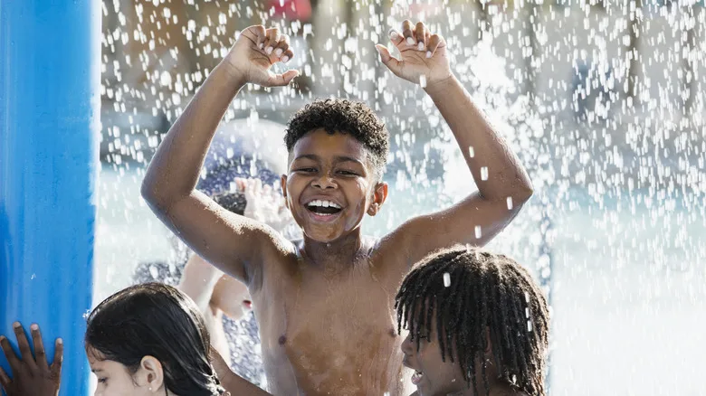 A 10 year old African-American boy having fun playing at a water park
