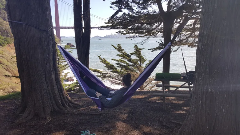 Camper in hammock by the water and Golden Gate Bridge