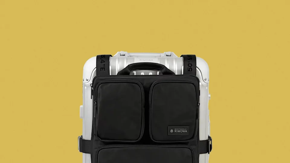 Black multi-pocket travel organizer attached to a silver hard-shell suitcase with black straps.