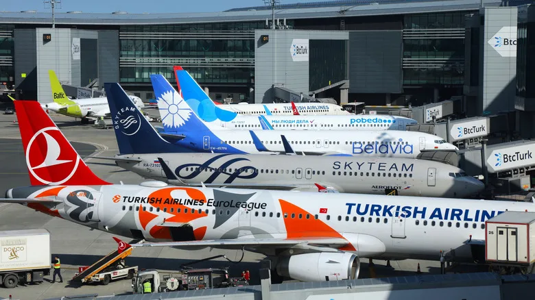 Multiple planes from multiple airlines sitting at an airport gate