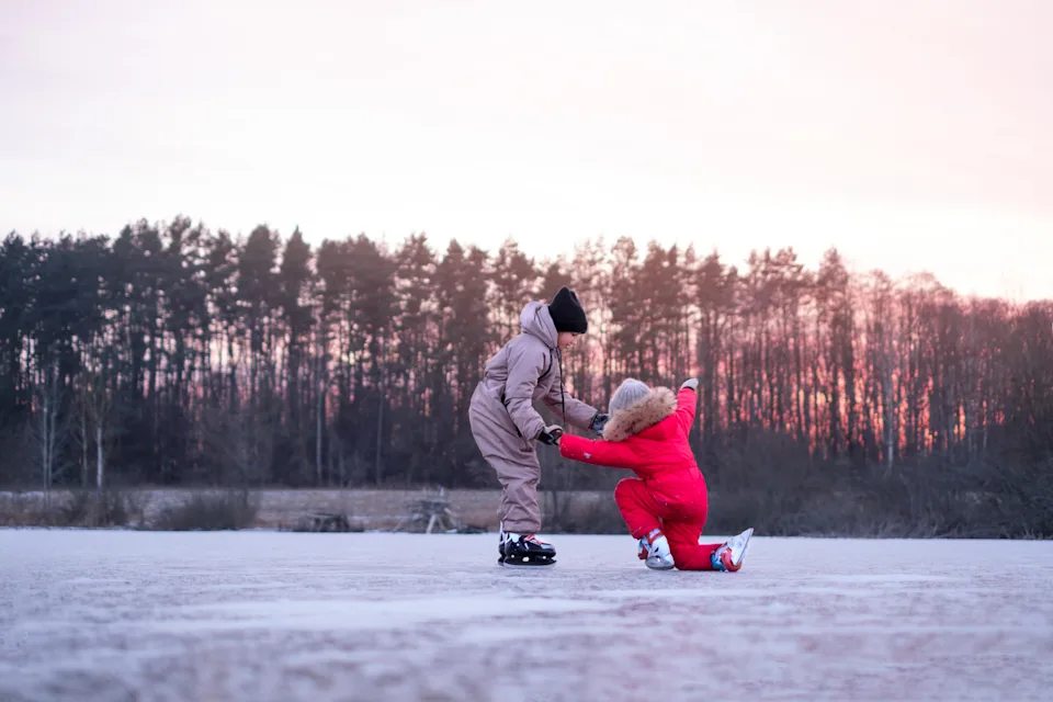 A girl helps a friend who fell while riding on canyons to get up. Outdoor winter sports activities