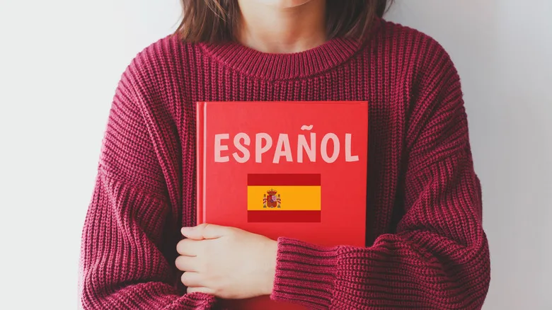 Person holding a Spanish textbook