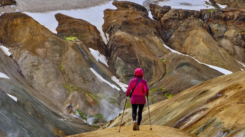 Person walking towards a mountain with patches of snow