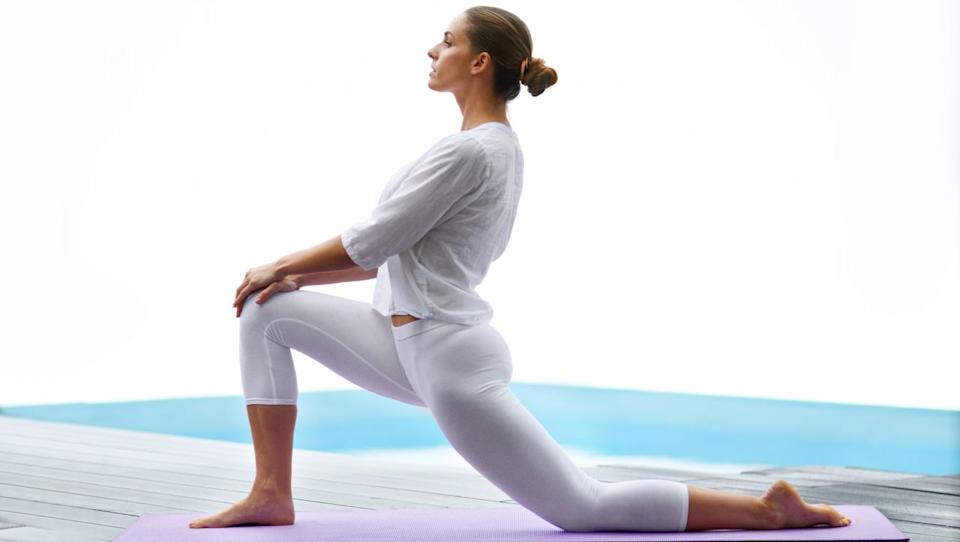  A woman leaning into a kneeling forward lunge. 