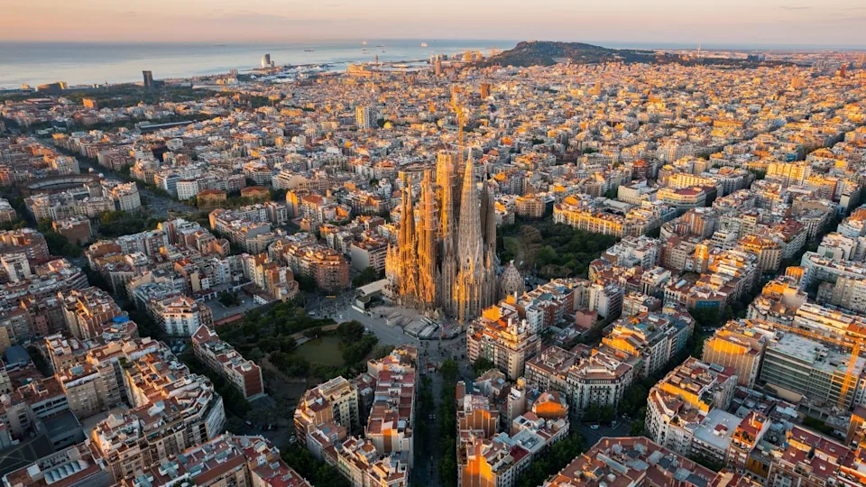 Aerial view of Barcelona Eixample residential district and Sagrada Familia Basilica at sunrise. Catalonia, Spain. Cityscape with typical urban octagon blocks