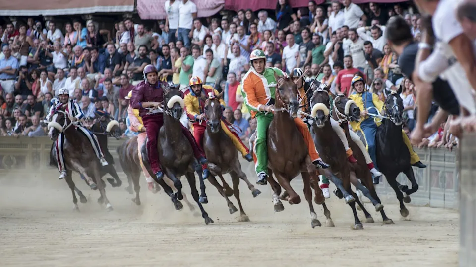 SIENA, ITALY - AUGUST 16, 2015 : Riders compete in the horse race "Palio di Siena" in the medieval square "Piazza del Campo" on August 16, 2015 in Siena, Italy. The race is held twice every year.