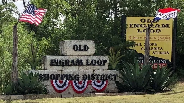 sign on rocks with banners and American flag infront of trees