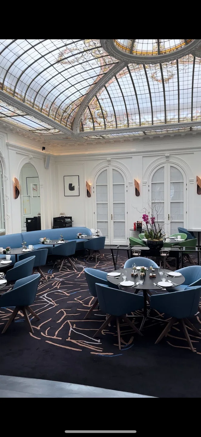 interior restaurant chez v at hotel vernet in paris featuring blue dining chairs and a stained glass ceiling dome
