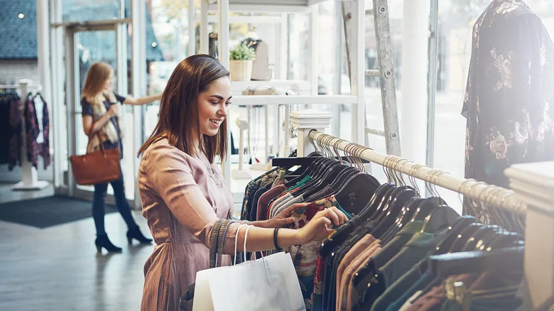 A young woman shopping at a clothing store, browsing the racks