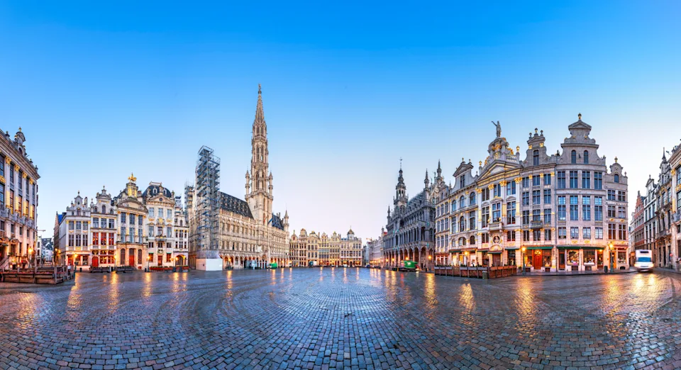 Panoramic view of Brussels' Grand Place, featuring ornate historic buildings and a cobblestone plaza under a clear sky