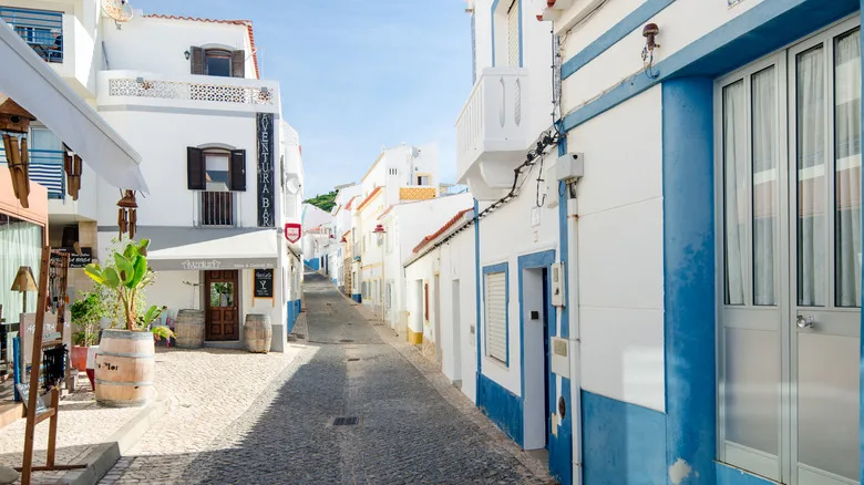 Narrow main cobbled street of Salema with blue and white houses