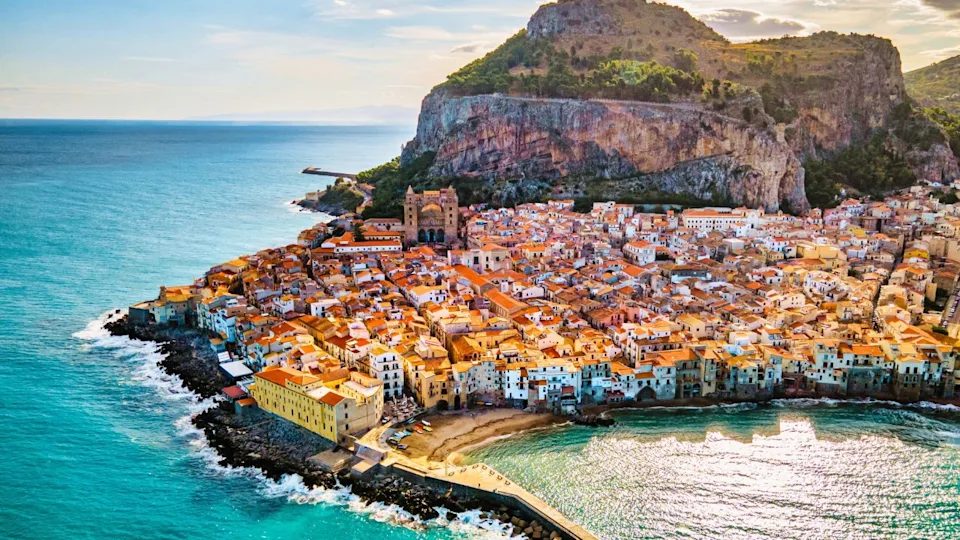 Drone view from above at the old town of Cefalu at sunset, medieval village of Sicily island, Province of Palermo, Italy. Europe. Cathedral of Cefalu
