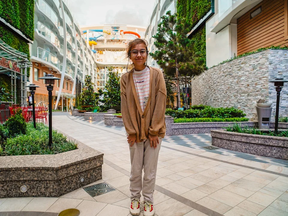 The author stands on an outdoor cruise ship deck with plants and waterslides in the background