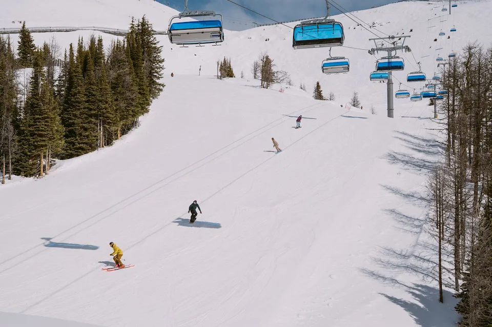 Sam Louise Skiers and snowboarders going down the snowy mountain.