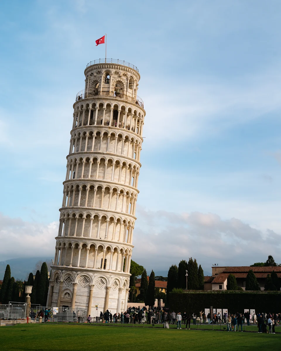 The Leaning Tower of Pisa against a blue sky, with tourists gathered around the base