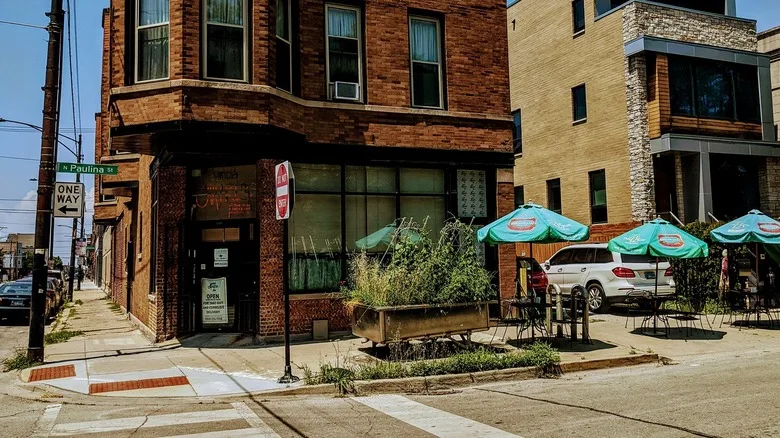 The red brick exterior of Uncle Mike's Place with tables and blue umbrellas outside