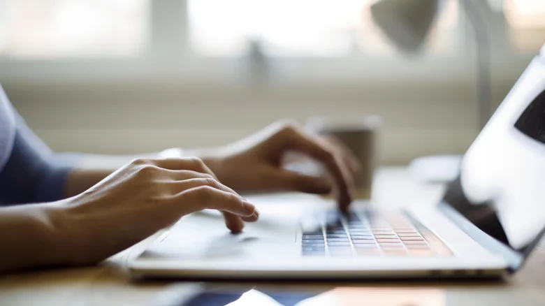 Profile shot of a person typing on a laptop