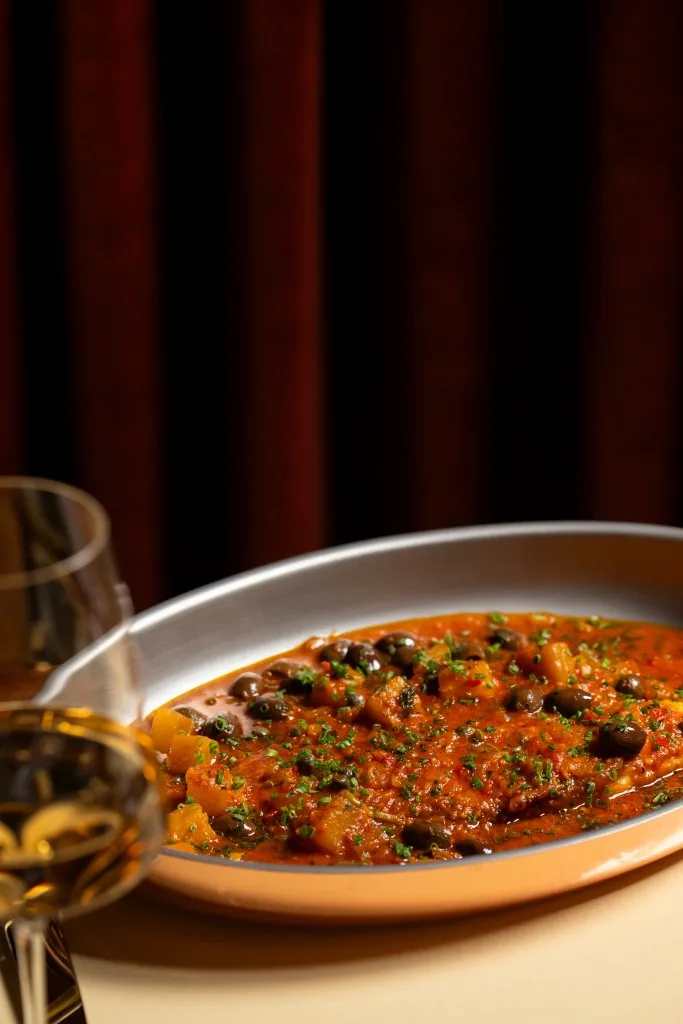 A pan filled with red sauce, olives and herbs. Courtesy of La Specialità