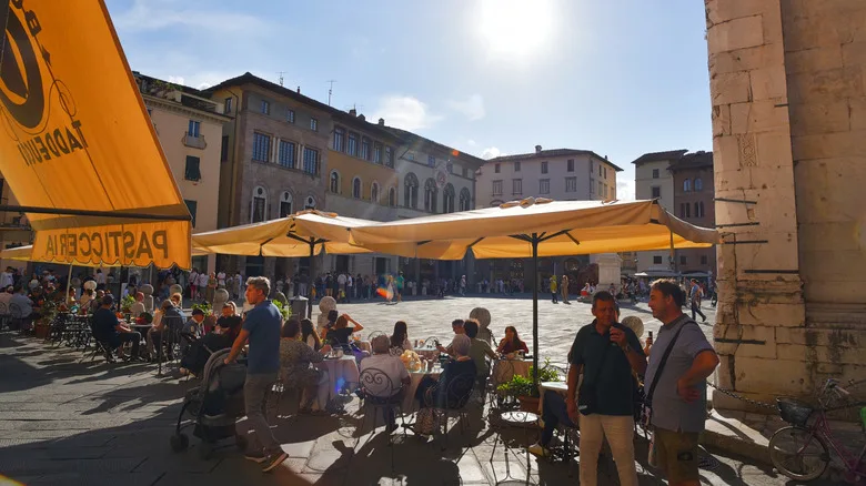 Cafe-goers sit under umbrellas in an outside seating area on the Il Campo in Siena