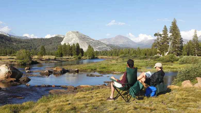 Two people on seats looking at a view of Yosemite's mountains and forests