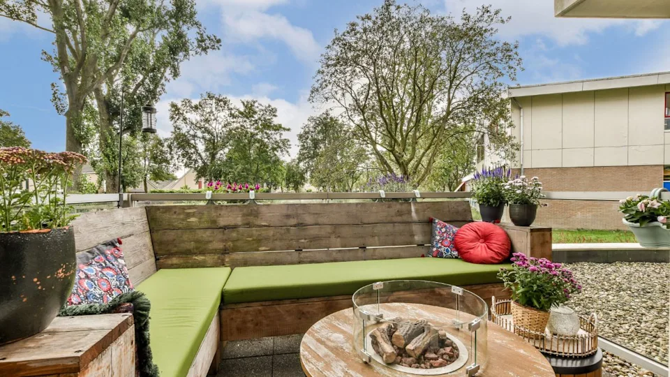 A beautifully designed outdoor lounge featuring comfortable seating, vibrant cushions, and lush trees, creating a tranquil space for relaxation.