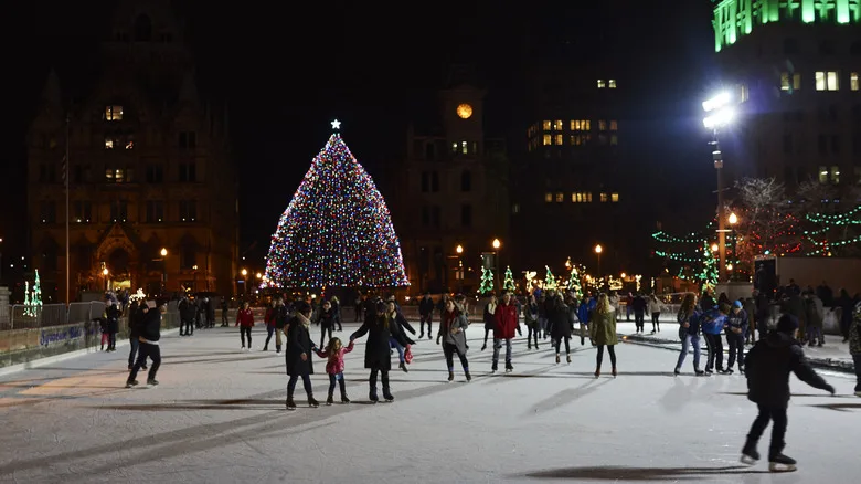 People ice skating outside in Syracuse with a Christmas tree in the background