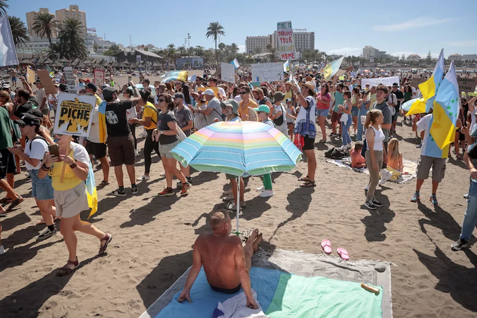 Protesters march on Las Americas beach during a demonstration to protest against mass tourism, in Arona on the Spanish Canary island of Tenerife, on Oct. 20, 2024. Thousands of flag-waving demonstrators hit the streets across Spain's Canary Islands today to demand changes to the model of mass tourism they say is overwhelming the Atlantic archipelago. Rallying under the slogan "The Canary Islands have a limit", demonstrators waving white, blue and yellow flags of the Canary Islands, marched by tourists sitting in outdoor terraces in Playa de las America before they rallied on the beach chanting "This beach is ours" as tourists sitting on sunbeds under parasol shades looked on.