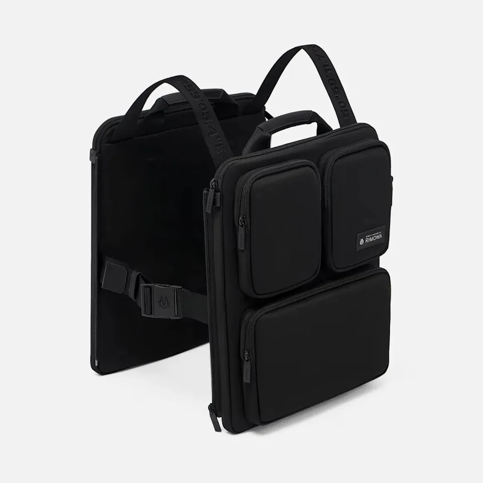 Black rectangular backpack with three zippered front pockets and padded shoulder straps.