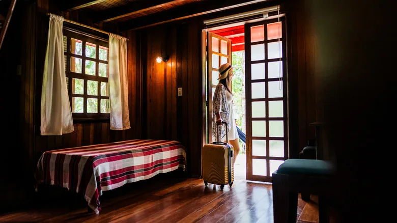 Female tourist with a suitcase in a wooden hotel room