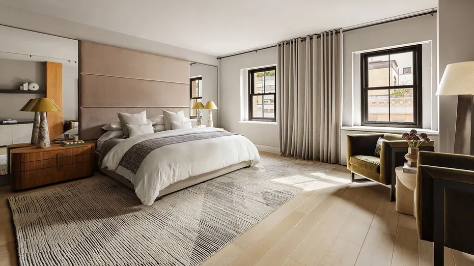 The primary bedroom features light hardwood floors and big windows.