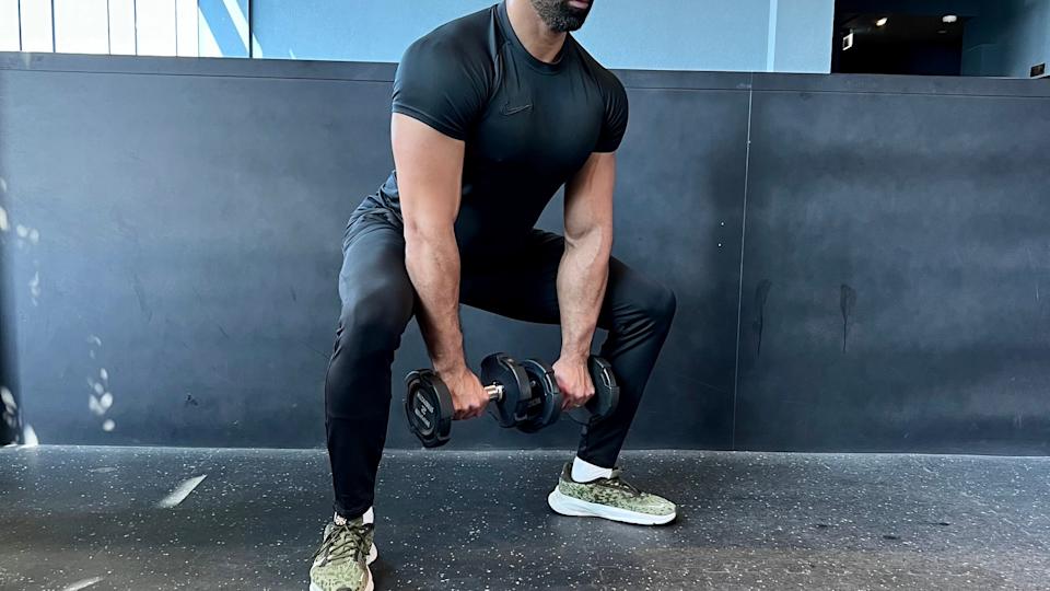 a photo of trainer Ali Malik performing a Dumbell Sumo Squat