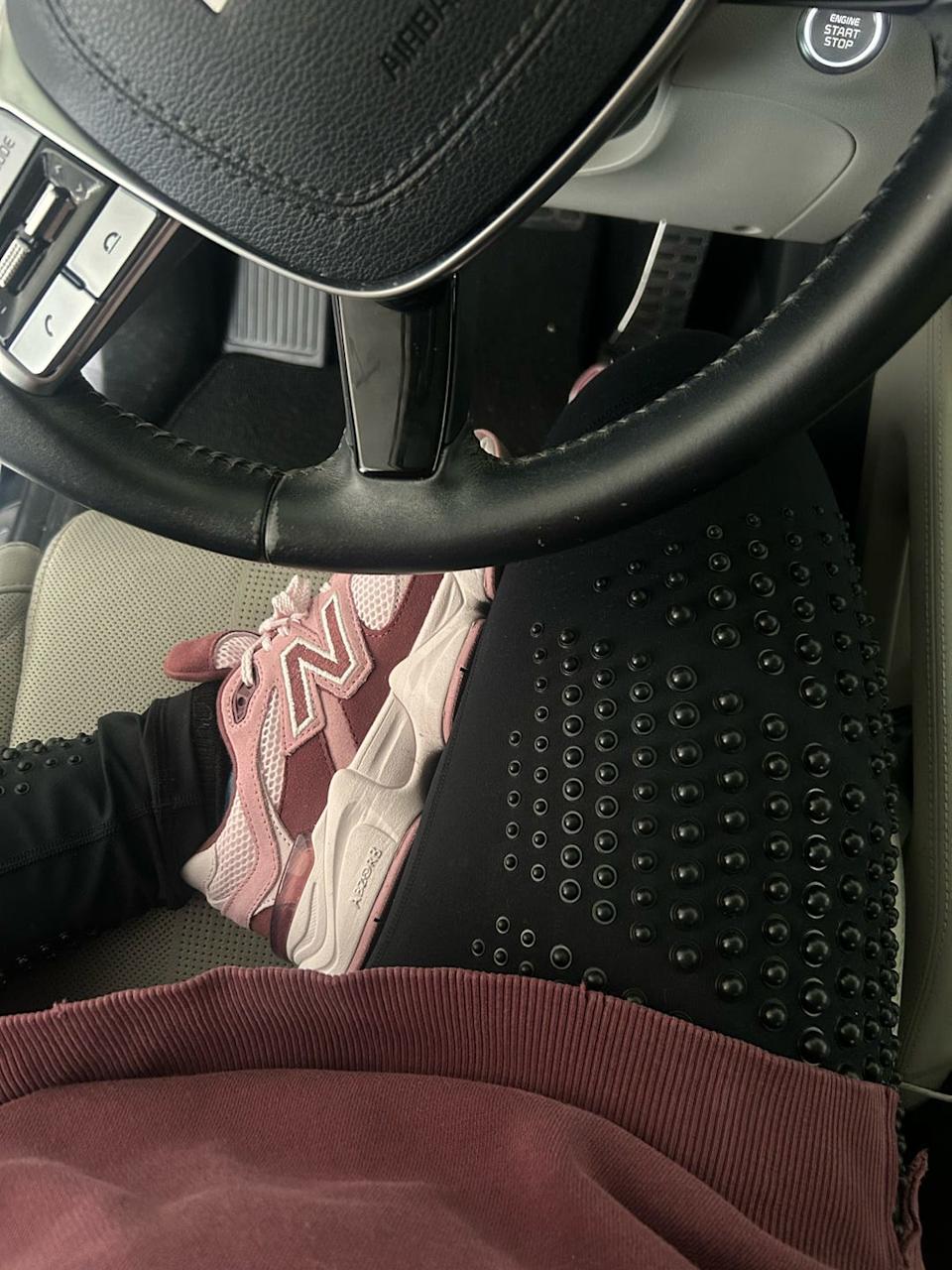 foot resting on car floor with a view of the steering wheel and gear shift
