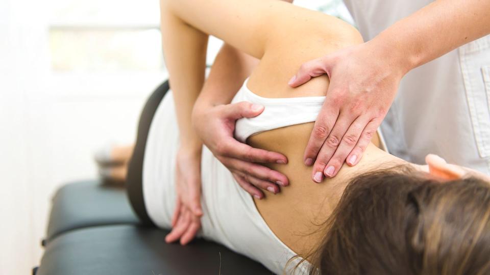A woman getting help stretching her upper body.