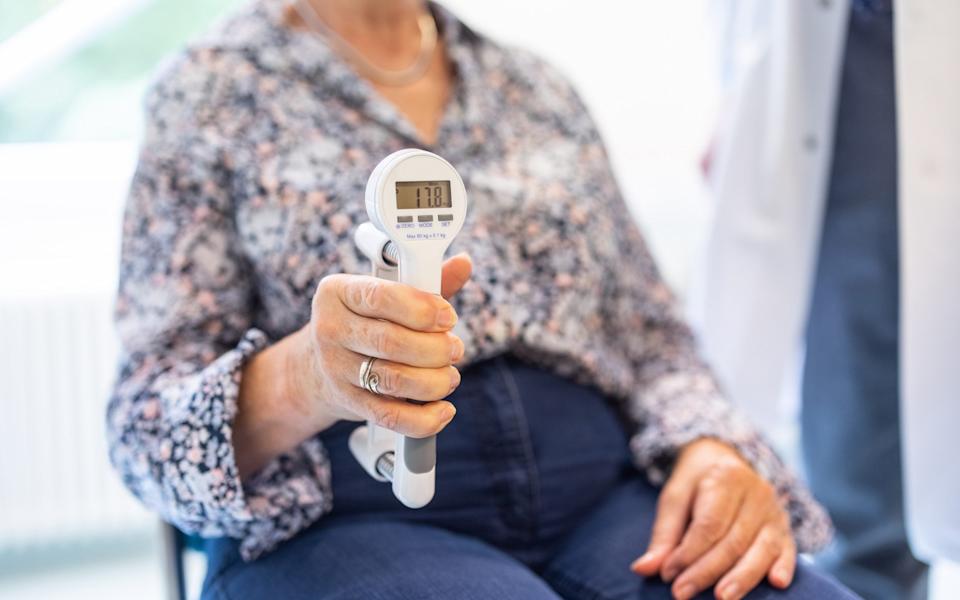 Close-up of a senior woman using hand dynamometer for grip strength test in clinic. Female patient having her hand grip strength test.