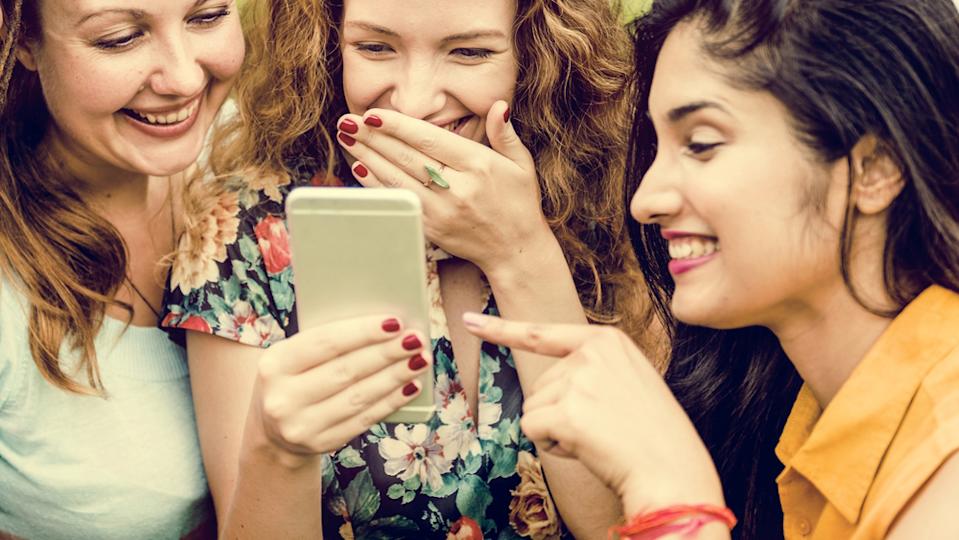 women laughing at something on a phone