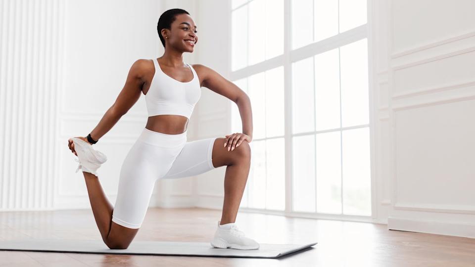 A woman stretching her hamstring on a mat.