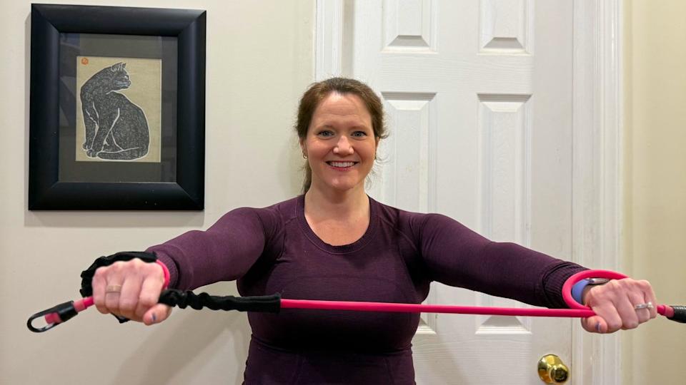 Woman holding exercise band in front of her.