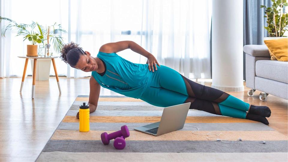  Woman in side plank on a yoga mat at home. 