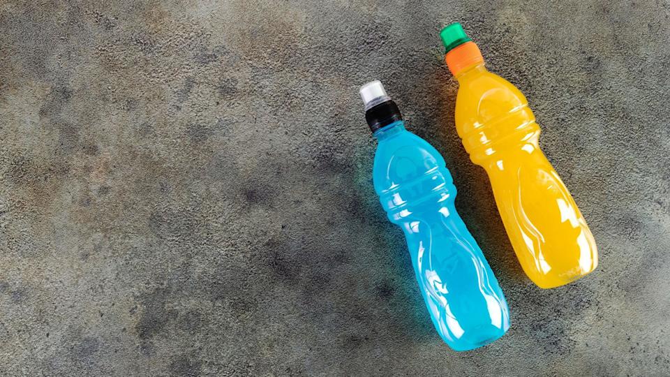 Blue bottle of isotonic drink, L-carnitine, sports energy drink on gray background. Bottle of fitness drink.