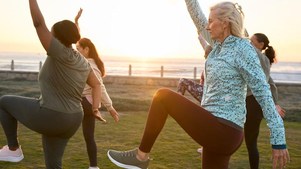 A group of mature exercisers balancing outside during a workout.